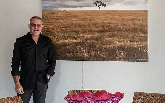 Cary poses in front of his photograph, “Series of One,” on the couple’s patio.