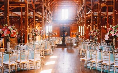 White daylight illuminates a wooden hangar prepared for a wedding dinner.