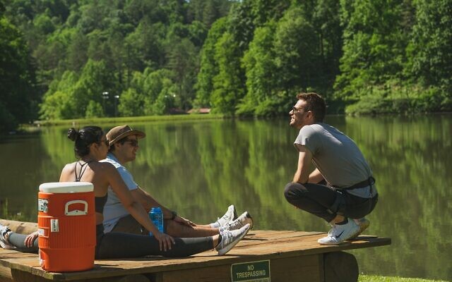 A trio of campers enjoy some rest and relaxation by the scenic lake.