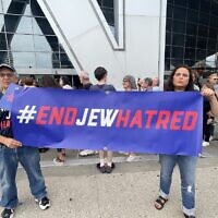 Jeffrey Jacobson and Cheryl Dorchinsky standing outside State Farm Arena before the Roger Waters concert to holding a #ENDJEWHATRED banner.