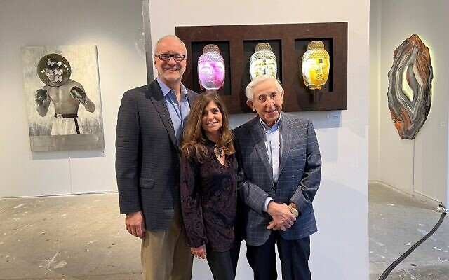(From left) Stephen Isaf, Cynthia Kerker Isaf, and Jack Kerker use Rose’s “Three-Headed Buddhas” as the background.