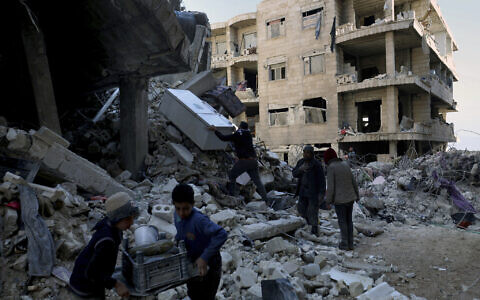 People remove furniture and household appliances out of a collapsed building after a devastating earthquake rocked Syria and Turkey in the town of Jinderis, Aleppo province, Syria, Tuesday, Feb. 7, 2023. (AP/Ghaith Alsayed)