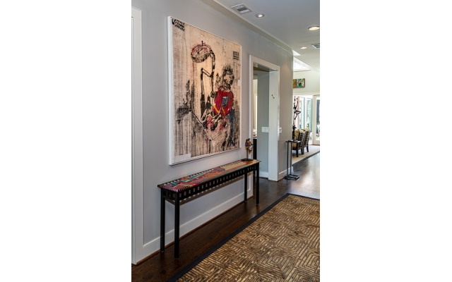 The large butcher painting in the entrance hall is by Zimbabwean artist Gareth Nyanhonfu. Below is a colorful detailed table by American artist, Barbara Brozic.