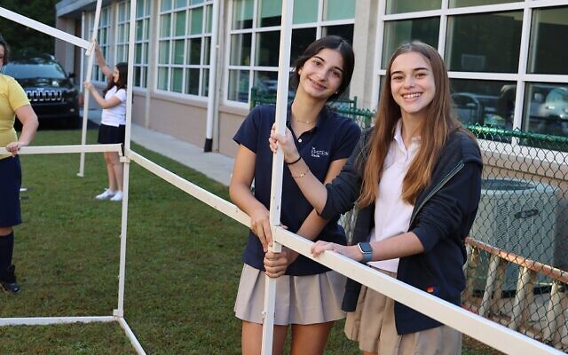 Following school tradition, Epstein Class of 2024 students, Layla Niess and Leighton Tritt, help build the school sukkah.