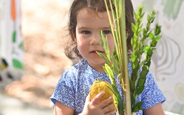 Epstein ECP student, Myers Bock, is learning the blessings to recite with her lulav and etrog in the sukkah.