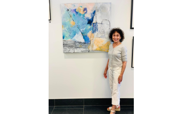 Aviva Stern stands in front of one of her works, “Pink Cloud/Blue Sea.”