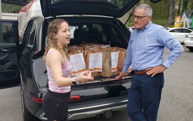 Sarah Menis, left, and CAC CEO Francis K. Horton III, right, chat about food insecurity as Menis drops off a donation at the CAC food pantry. 