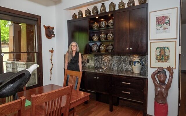 Amy stands in the dining room by one of their favorite collections Lanier Meaders, Jug Pottery.  