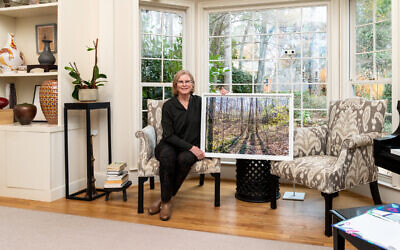 Judy Lampert holds a photograph taken by Lucinda Bunnen of the woods on her trail. The Bunnen estate is now destined to be a nature preserve for the city // Photo Credit: Howard Mendel