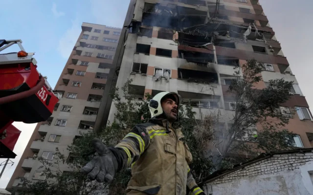 A firefighter calls out his colleagues at the scene of an explosion in a residential compound in northern Tehran, Iran, June 13, 2025 // Photo Credit: Vahid Salemi/AP/Times of Israel