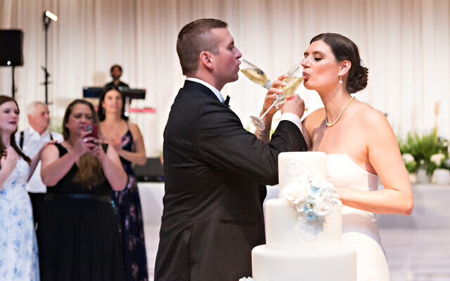 After the cake cutting, the bride and groom wrap their arms for a champagne toast.