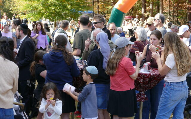 Attendees enjoy their barbeque while a young girl focuses on a flower.