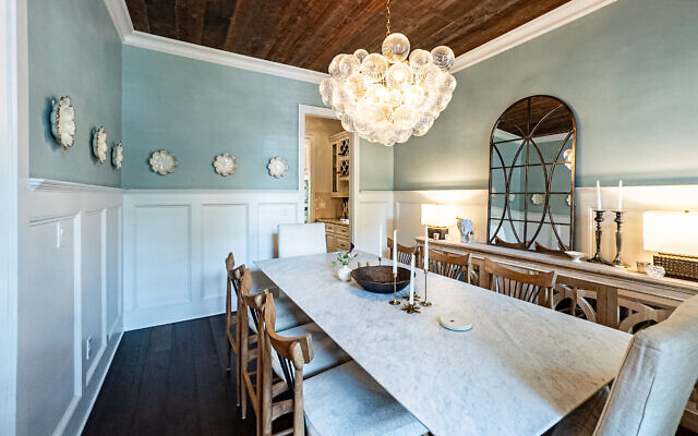 The dining room ceiling is done in barn wood. Rosenzweig used Lenox china to envelope the walls around the table. The chandelier is Visual Comfort.