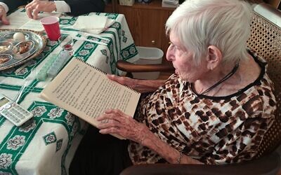 A JBI Library patron reads from a large-print Passover Haggadah.