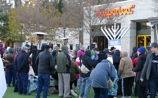 The gathered crowd returns to their festivities right after the menorah is lit for the Sunday event. The gathered crowd returns to their festivities right after the menorah is lit for the Sunday event.