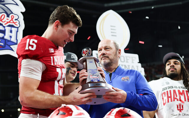 In one of his final acts as CEO of the Peach Bowl, Gary Stokan (center) presents Indiana Hoosiers quarterback Fernando Mendoza with the S. Truett Cathy Most Outstanding Player Award after his team’s resounding win over Oregon in the CFP Semifinal // Photo Credit: Chick-fil-A Peach Bowl In one of his final acts as CEO of the Peach Bowl, Gary Stokan (center) presents Indiana Hoosiers quarterback Fernando Mendoza with the S. Truett Cathy Most Outstanding Player Award after his team’s resounding win over Oregon in the CFP Semifinal // Photo Credit: Chick-fil-A Peach Bowl