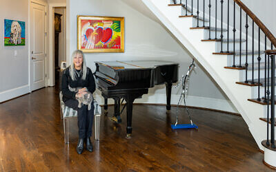 Cheryl Henos greets guests in her entry foyer by Peter Max’s, “Hearts.” The pet painting (left) is by Madison Latimer. Rescue cat, Lucy, enjoys the lap perch // All photos by Howard Mendel