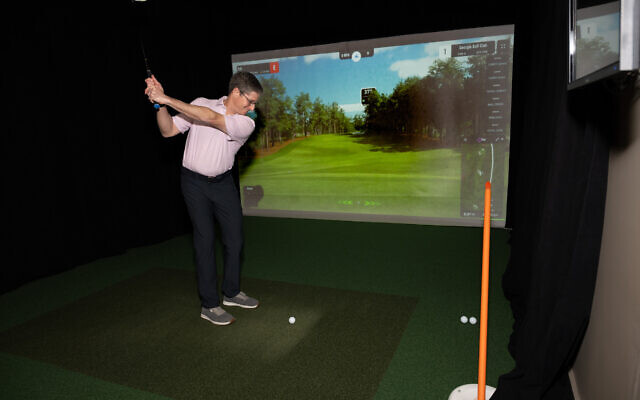 Erik, a corporate lawyer specializing in mergers and acquisitions, perfects his swing in his above-garage Ace Indoor Golf Simulator. 