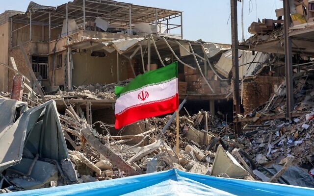 An Iranian flag is placed amid rubble and debris next to a destroyed residential building near Ferdowsi Square in Tehran on March 3 // Photo Credit: Atta Kenare/AFP/Times of Israel
