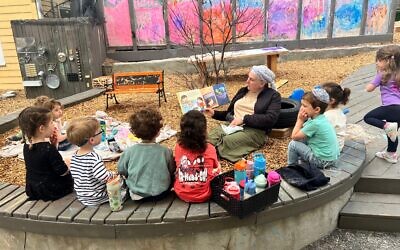 Adi Feen reads to her class outside on the playground.