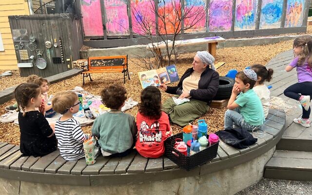 Adi Feen reads to her class outside on the playground. Adi Feen reads to her class outside on the playground.