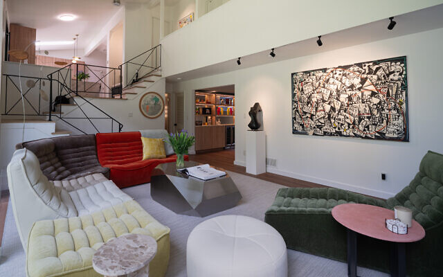 The expansive great room has a feature wall that is often rotated. Here is original, “Urban Cubism,” by Brooklyn artist, Flore and a bronze bust by Vincent Beaufils-Hourdigas. The room is anchored by a multi-colored Bova sofa, midcentury modern chaise velvet, suede, and leather texture. The Vesta jewel-shaped coffee table centers the room.   