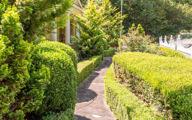 The sunny ranch peaks behind trimmed hedges. 