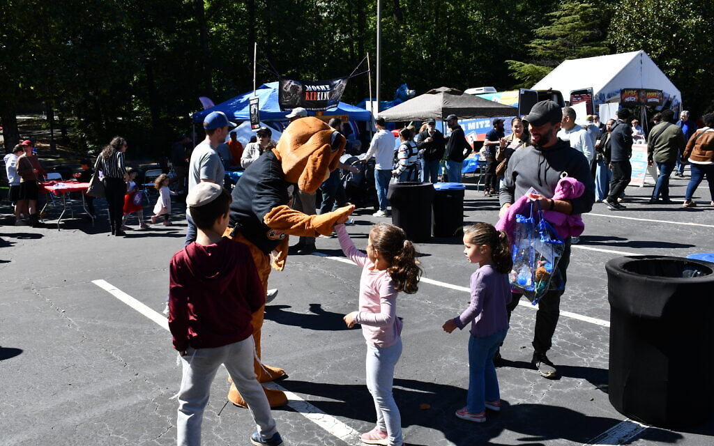 Lou Ladinsky, dressed in a dog costume, greets some children to their amusement.