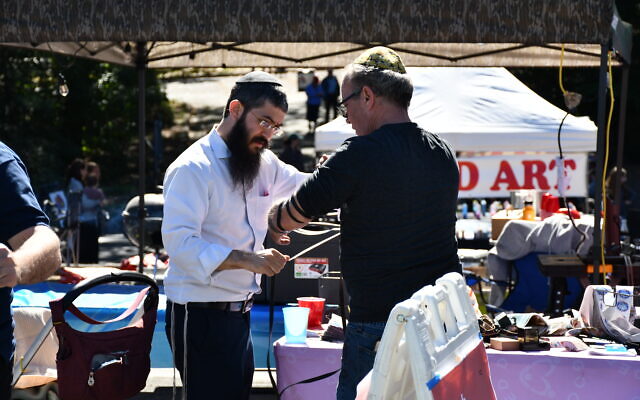A festival attendee takes a moment to wrap tefillin.