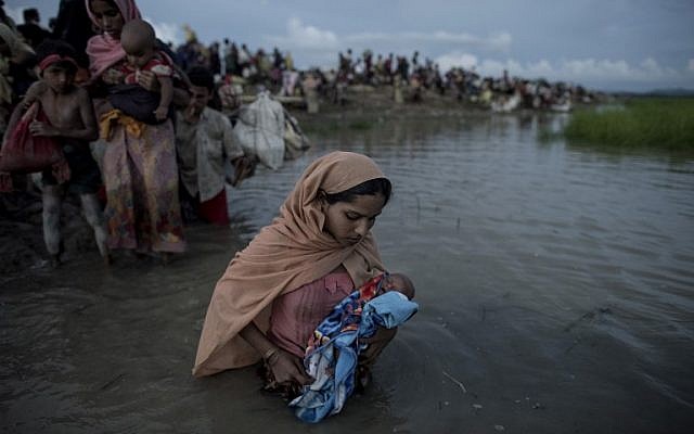 Illustrative: Rohingya refugees wading while holding a child after crossing the Naf River from Myanmar into Bangladesh in Whaikhyang on October 9, 2017. (AFP/Fred Dufour)