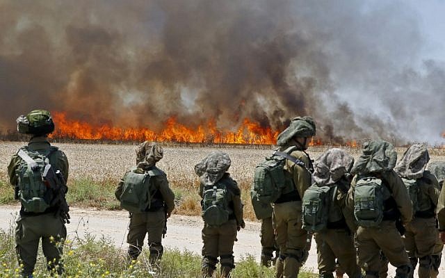 Israeli soldiers walk amidst smoke from a fire in a wheat field near the Kibbutz of Nahal Oz, along the border with the Gaza Strip, which was caused by incendiaries tied to kites flown by Palestinian protesters from across the border., May 14, 2018. (Jack Guez/AFP)