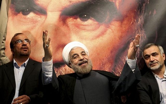 Hasan Rouhani, center, poses before a large portrait of the late Iranian revolutionary founder Ayatollah Khomeini, the day after being elected to Iran's presidency, on June 15, 2013 (Photo credit: AP/Ebrahim Noroozi)
