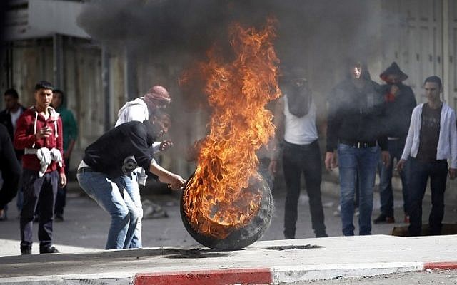 Palestinians set fire to tires during a large protest in Hebron in February (photo credit: Thomas Coex/AFP)