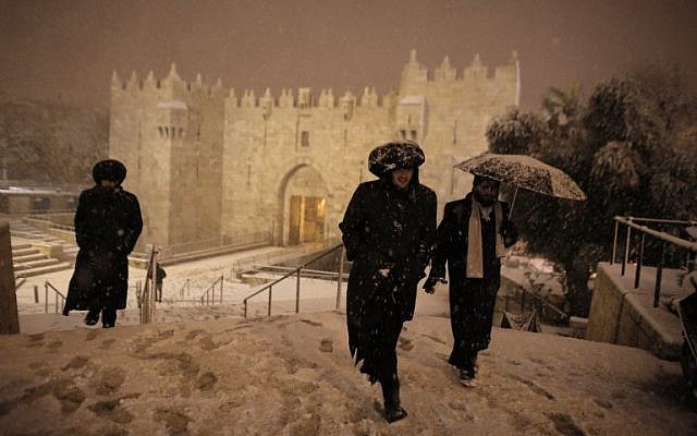 Ultra-Orthodox Jewish men walk near Damascus Gate in Jerusalem’s Old City as snow falls on February 19, 2015. (photo credit: AFP PHOTO / AHMAD GHARABLI)