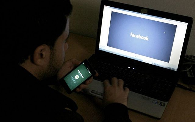 Illustrative image of a man in front of a computer with the Facebook logo, February 26, 2014 (Abed Rahim Khatib/Flash90)