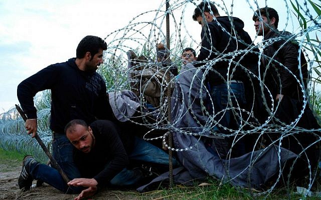 Syrian refugees cross into Hungary underneath the border fence on the Hungarian-Serbian border near Roszke, Hungary, Aug. 26, 2015 (AP Photo/Bela Szandelszky, File)