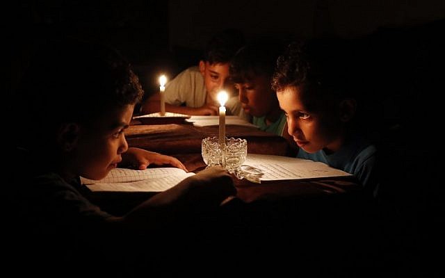 Illustrative. Palestinian children at home reading books by candle light due to electricity shortages in Gaza City, June 13, 2017. (AFP/ Thomas Coex/File)