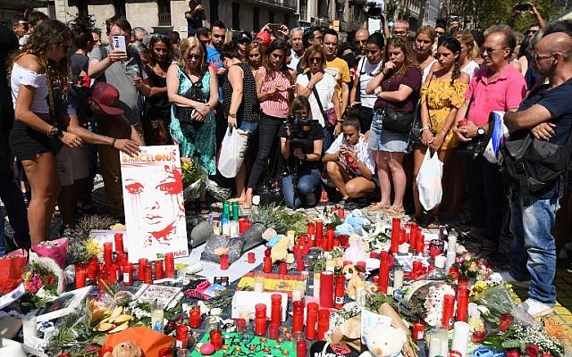 People stand next to flowers, candles and other items set up on the Las Ramblas boulevard in Barcelona as they pay tribute to the victims of the Barcelona attack on August 18, 2017. (AFP/PASCAL GUYOT)