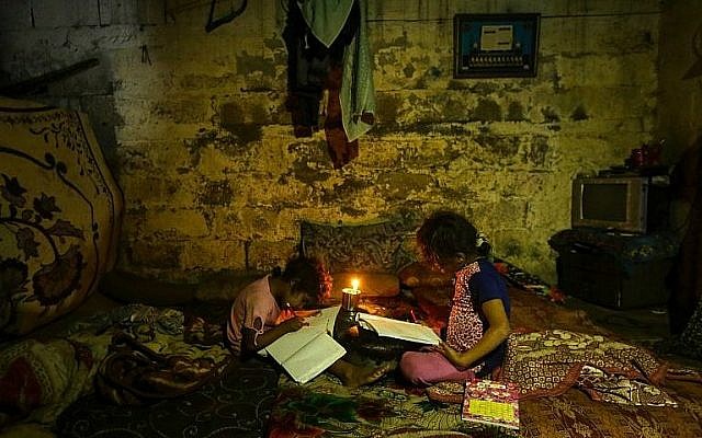 Illustrative: Palestinian children do their homework by candlelight during a power outage in Gaza City on September 11, 2017. (AFP Photo/Mahmud Hams)