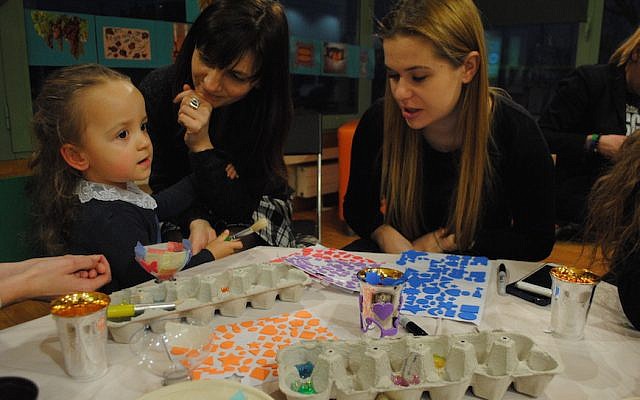 Sara Zielinski, with her mother Elizabeth, center, and a volunteer at a pre-Shabbat program at the Jewish Community Center of Krakow. Sara is part of the inaugural class of Frajda, the first pluralistic Jewish nursery and preschool in Krakow since World War II. (Courtesy of Jewish Community Center of Krakow/via JTA)