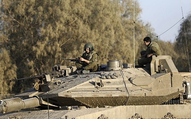 Illustrative: Israeli soldiers sit on a tank close to the Israeli border with the Gaza Strip on October 30, 2017, near Kibbutz Kissufim in southern Israel. (AFP PHOTO/MENAHEM KAHANA)