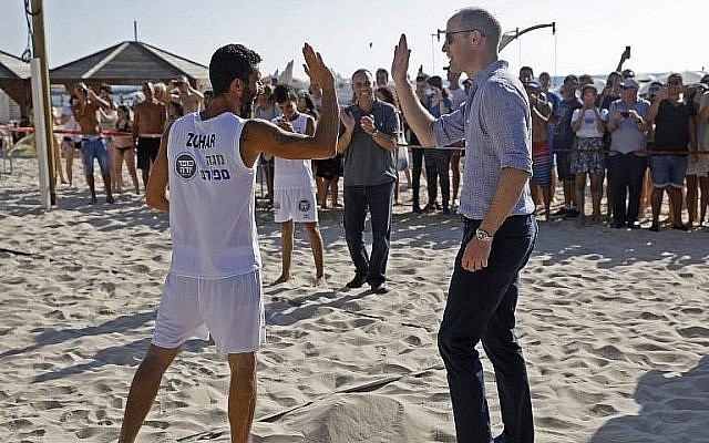 Britain's Prince William (R) high-fives a beach volleyball player during a visit with the mayor of Tel Aviv in the coastal city on June 26, 2018 (AFP PHOTO / POOL / MENAHEM KAHANA)