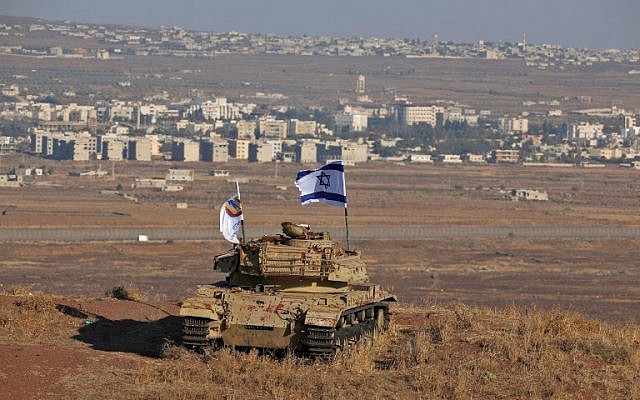 An Israeli flag flutters above the wreckage of an Israeli tank sitting on a hill in the Israeli-occupied sector of the Golan Heights and overlooking the border with Syria and the town of Quneitra, on October 18, 2017. (Photo by JALAA MAREY / AFP)