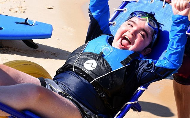 Adi Goldschmiedt, who has Duchenne muscular dystrophy, sports a huge smile after “catching a wave” off the coast of Bat Yam, south of Tel Aviv. (Larry Luxner)
