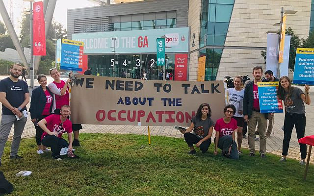 All That's Left activists stand in front of a banner reading, 'We need to talk about the occupation,' at the Jewish Federations of North America General Assembly in Tel Aviv, October 24, 2018. (Steven Davidson/ Times of Israel)