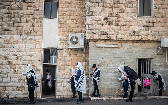Illustrative. Jewish men pray outside a synagogue while maintaining social distancing as part of the campaign against the coronavirus outbreak, in Bayit Vegan, Jerusalem, on March 22, 2020. (Yonatan Sindel/Flash90)