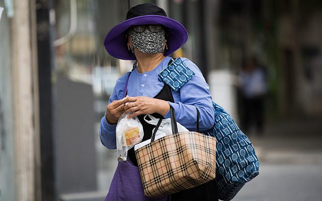 An Israeli woman, wearing a face mask for fear of the coronavirus as she walks in downtown Jerusalem on April 2, 2020. (Nati Shohat/Flash90)