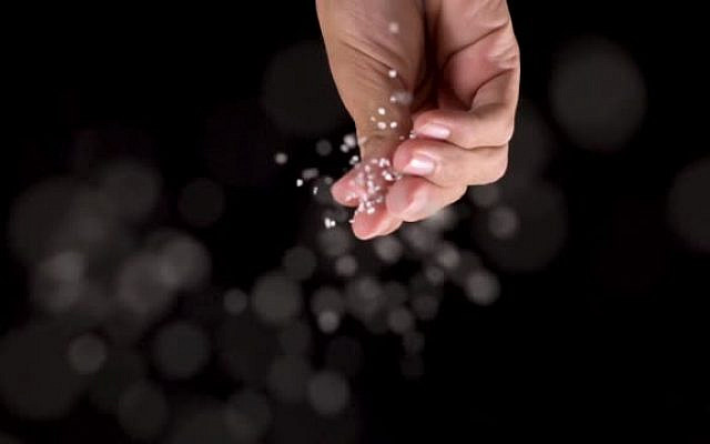 Slow motion with center composition: Sprinkling salt on top of camera view with copy space and black background.