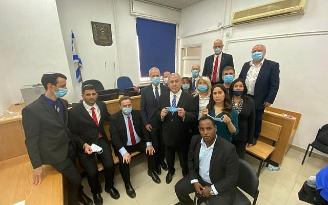 Likud lawmakers demonstrate spotty compliance with the social distancing and hygiene regulations. Prime Minister Benjamin Netanyahu, alongside fellow Likud lawmakers at the Jerusalem District ahead of the opening hearing of his corruption trial on May 24, 2020. With Netanyahu (from left): Ariel Kelner (Likud candidate); Shlomo Karai MK; Finance Minister Israel Katz; Education Minister Yoav Gallant; Nir Barkat MK; Minister without Portfolio Tzachi Hanegbi; Keti Shitrit MK; Gadi Yevarkan MK; Minister of Public Security Amir Ohana; Mai Golan MK; Minister of Intelligence Eli Cohen; Transportation Minister Miri Regev; Minister for Liaison between the Government and the Knesset David Amsalem. (Prime Minister Benjamin Netanyahu/Twitter)