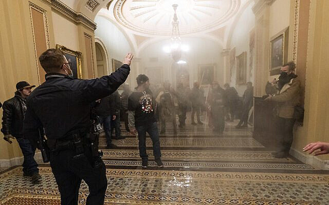 Smoke fills the walkway outside the Senate Chamber as supporters of President Donald Trump are confronted by U.S. Capitol Police officers inside the Capitol, Wednesday, Jan. 6, 2021 in Washington.  (AP Photo/Manuel Balce Ceneta)